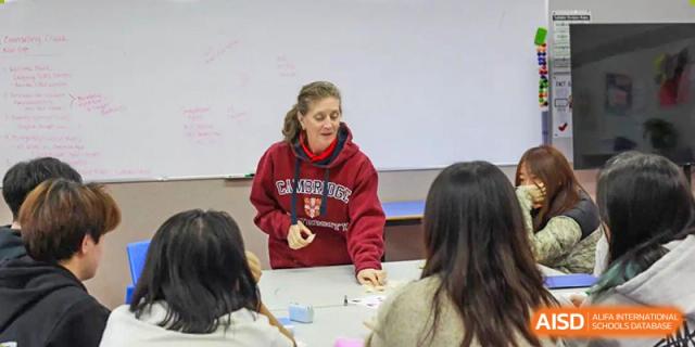 A teacher standing and speaking to a group of students in a classroom at BaiShan AWS High School.