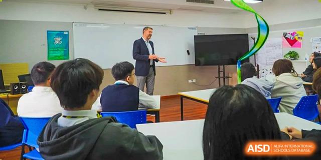 A teacher giving a presentation to students seated at desks at BaiShan AWS High School.