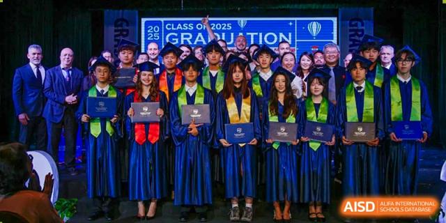 Students in graduation caps and gowns holding their diplomas at BaiShan AWS High School's graduation ceremony.