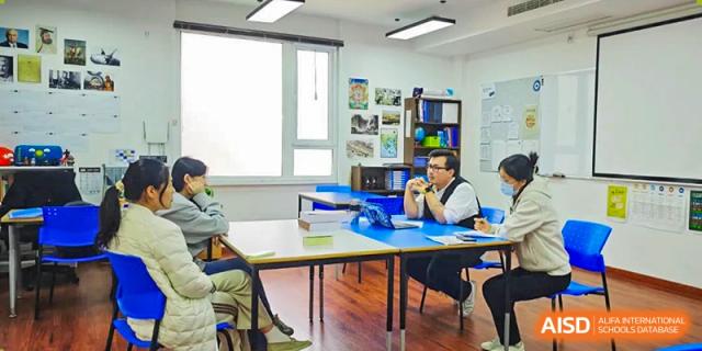 Students collaborating around a table in a classroom at BaiShan AWS High School.