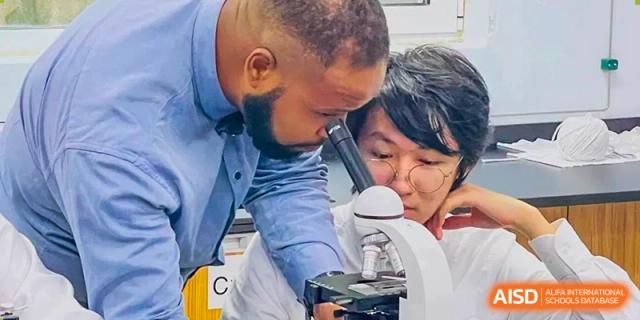 A teacher looking at a science experiment with students at BaiShan AWS High School.