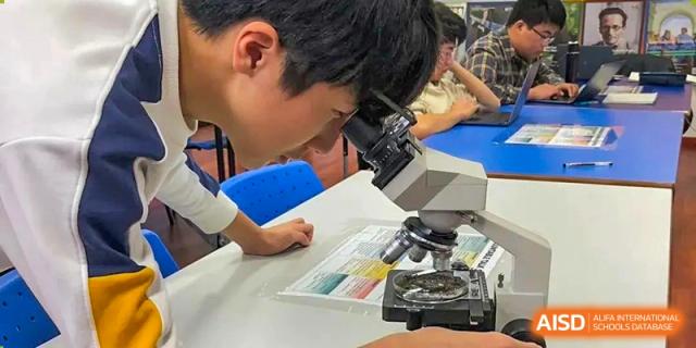 A student looking into a microscope during a science class at BaiShan AWS High School.