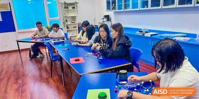 A group of students smiling and working together on a project at BaiShan AWS High School.