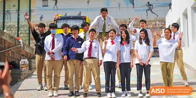 BaiShan AWS High School students posing for a group photo outside, with some standing on the stairs of a bus.