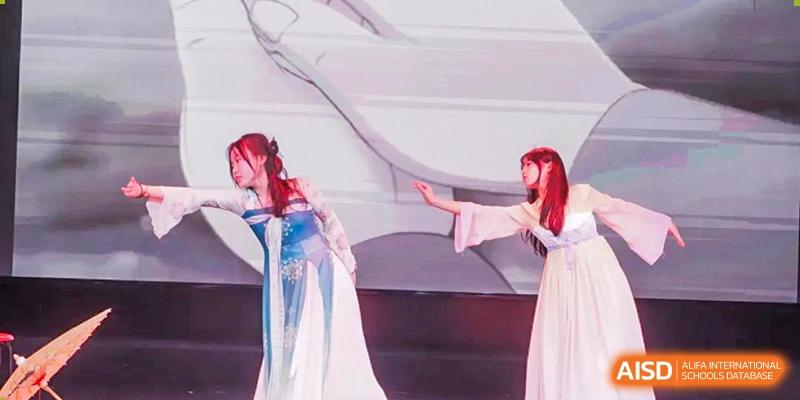 A student performing a graceful dance in a white flowing dress at a BaiShan AWS High School event.