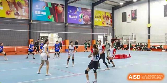 Students playing volleyball in an indoor court at BaiShan AWS High School.