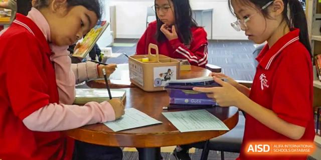 Students are collaborating on a project or assignment at a table in a classroom at Chengdu International School.