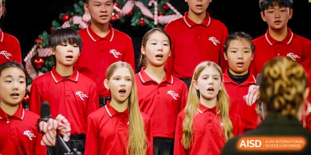 A group of students in red shirts is singing during a performance at Chengdu International School.