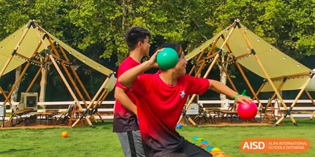 A male student in a red shirt is playing a game with a green ball at Chengdu International School.