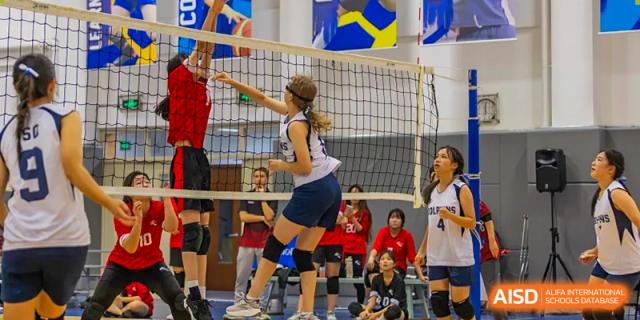 A female student is about to hit a volleyball over a net during a game at Chengdu International School.