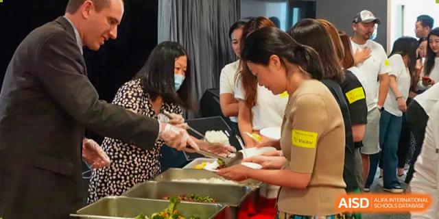 A group of people is getting food from a buffet line at Chengdu International School.