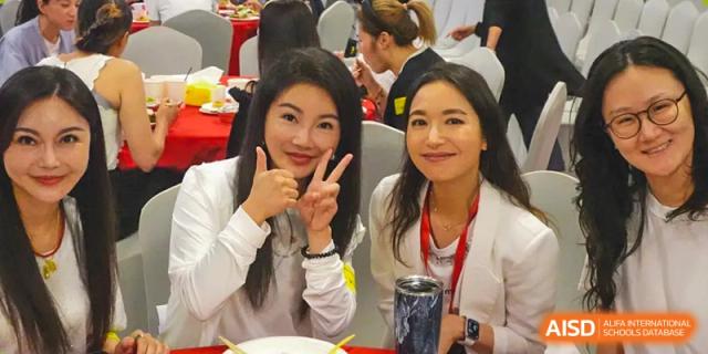 Two young women are smiling and making a peace sign at a social gathering at Chengdu International School.