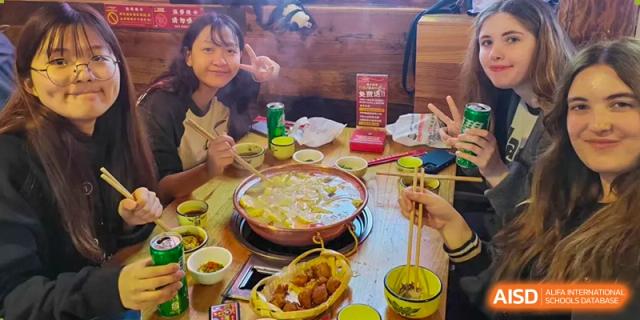 A group of students is sitting around a hot pot at a table, enjoying a meal together at Chengdu International School.