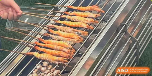 Large shrimp are cooking on a barbecue grill at Chengdu International School.