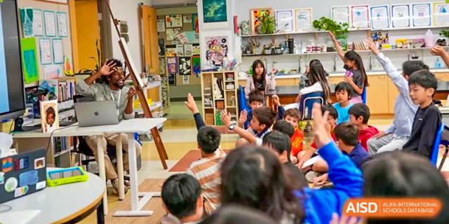 A student in a classroom at Shanghai American School is raising their hand to ask a question.