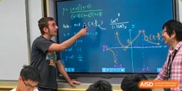 A teacher at Shanghai American School is pointing to an equation on a smart board during a math class.