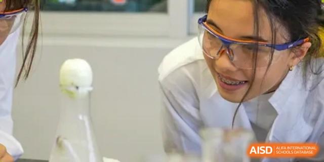 A male teacher at Shanghai American School is smiling while interacting with a student.