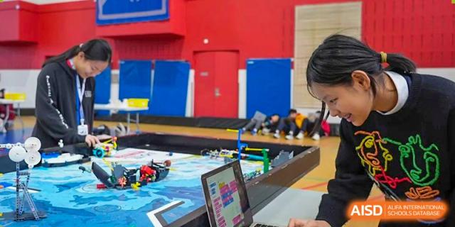 Students at Shanghai American School are working on a robotics project with Lego pieces and a laptop.