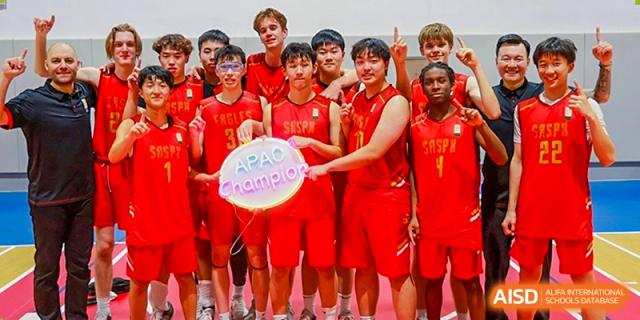 The Shanghai American School boys' basketball team is celebrating their championship win and posing with a trophy.