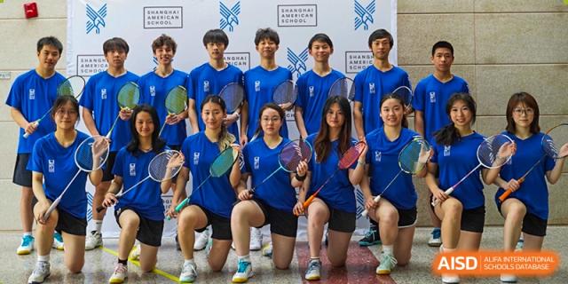 A group of students from Shanghai American School is posing with badminton rackets during a sports event.