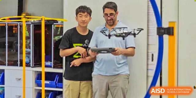 A student and an adult at Shanghai American School are holding a drone and its controller.