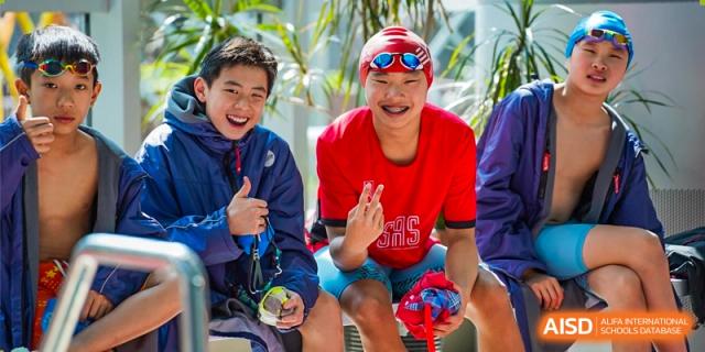 Two students from Shanghai American School are smiling and posing with their swimming medals.