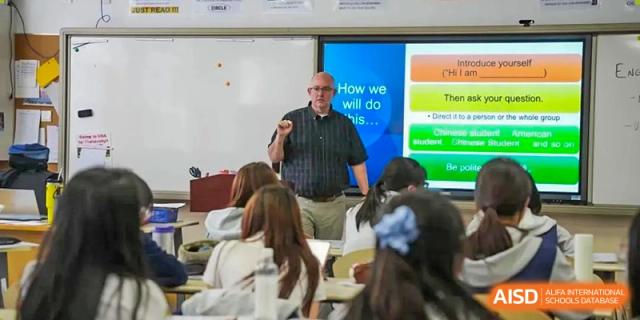 Teacher giving a lecture in a classroom, standing in front of a projector screen or whiteboard, Beijing Etown Academy International Department