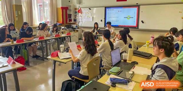 Students working on laptops and listening in a brightly lit classroom setting, Beijing Etown Academy International Department