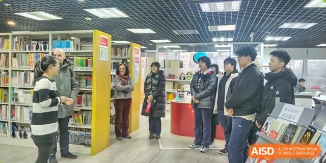 Several people standing in an indoor area that appears to be a library or bookstore, Beijing Etown Academy International Department