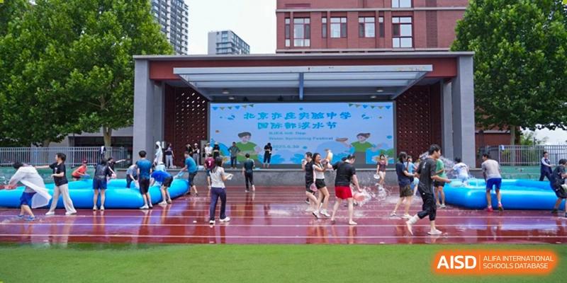 Students participating in an outdoor sports event on a red running track with a large digital screen in the background, Beijing Etown Academy International Department