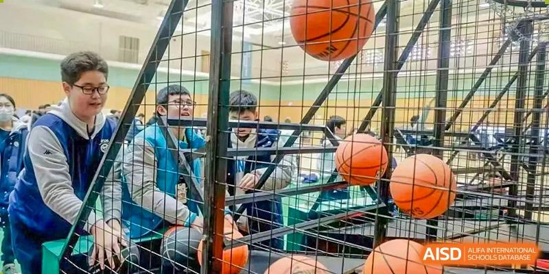 Students looking through the metal bars of a sports cage or enclosure containing basketballs, Beijing Etown Academy International Department