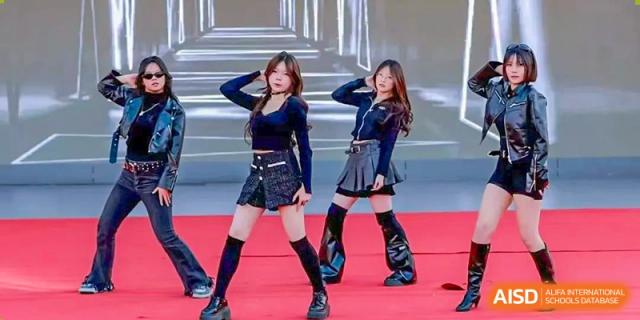 Two female dancers in black, long-sleeve tops and skirts performing on a bright red stage, Beijing Etown Academy International Department