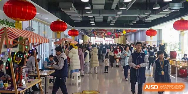 Crowd of people gathered indoors at an event decorated with red Chinese lanterns, Beijing Etown Academy International Department