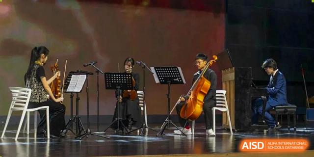 Students performing chamber music, one playing the cello and another reading music at a stand, Beijing Etown Academy International Department