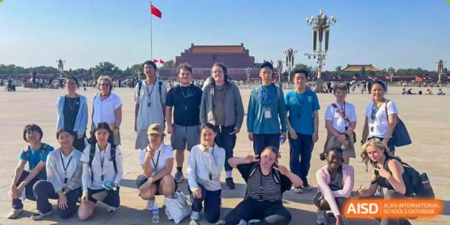 A group of students and adults posing for a casual photo outdoors in front of a historic building, Beijing Etown Academy International Department