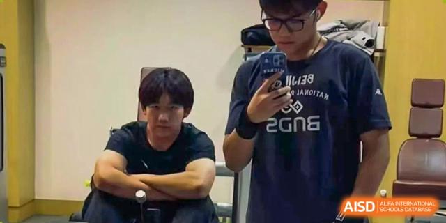 Two young male students, one holding a phone to take a selfie or photo, Beijing Etown Academy International Department
