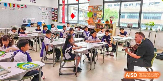 A group of young students from Cogdel Cranleigh School Changsha seated at their desks in a classroom, focused on an individual or group assignment.