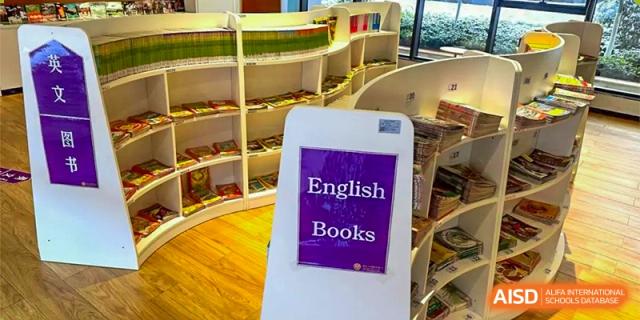 A sign in the Cogdel Cranleigh School Changsha library pointing to the section for "English Books" among the curved bookshelves.