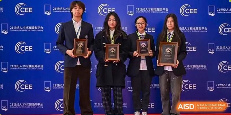 Three Cogdel Cranleigh School Changsha students, two girls and a boy, standing on stage in formal wear and holding award plaques after a competition or ceremony.