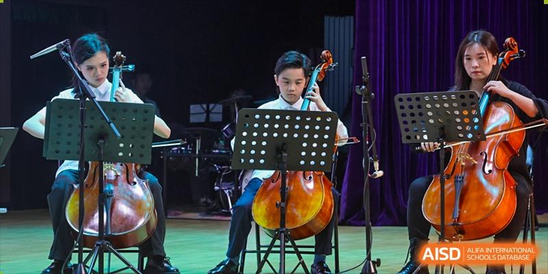 A male student from Cogdel Cranleigh School Changsha seriously playing the cello in a musical performance or practice session.
