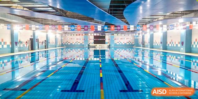 The indoor swimming pool facility at Cogdel Cranleigh School Changsha, showing multiple empty lanes and hanging banners.