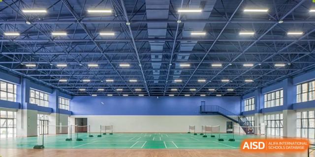The large indoor sports hall or gymnasium at Cogdel Cranleigh School Changsha, featuring a blue and green court marked for various sports.