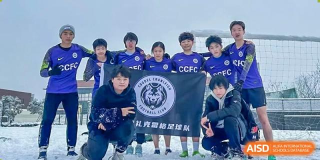The Cogdel Cranleigh School Changsha soccer team posing together on a field with their team banner and crest.