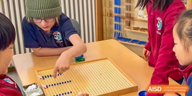 An AISB-Hope International student working with wooden math manipulatives on a pegboard, focusing on academic skills.