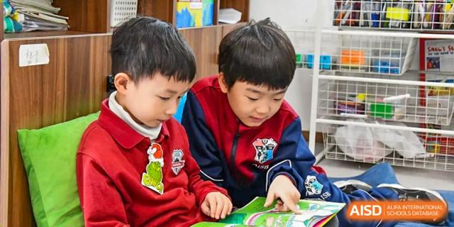 Two AISB-Hope International students concentrating on a book or task together in a classroom setting.