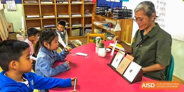AISB-Hope International students engaged in a hands-on activity around a red table in a well-equipped classroom.