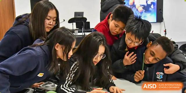 A group of AISB-Hope International students collaborating on a writing or reading task in a classroom.