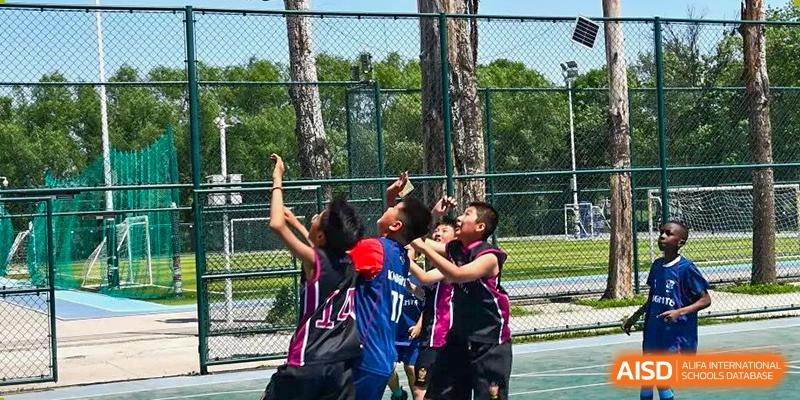 AISB-Hope International students playing an intense outdoor basketball game, jumping for the ball in a moment of action.