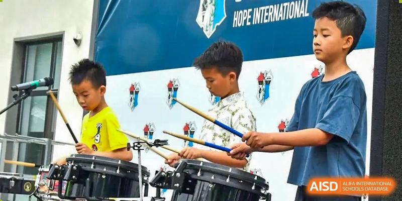 An AISB-Hope International student playing the drums energetically at a school event.