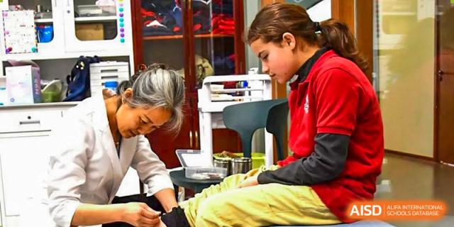 A young student receiving first aid or care from a staff member at AISB-Hope International.